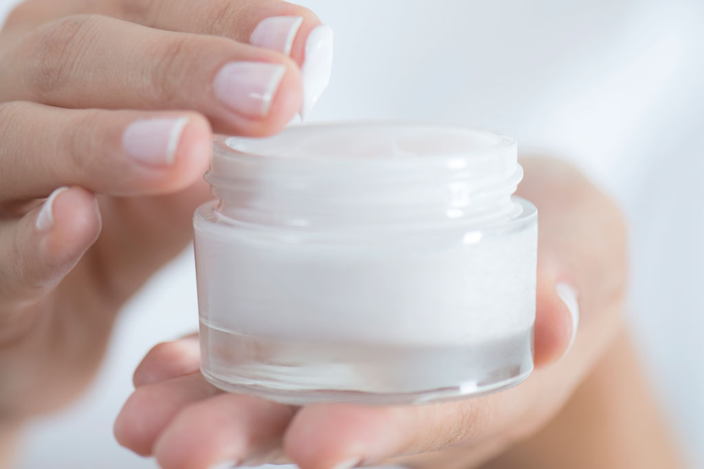 Female hand holding moisturizer in hand, horiztonal