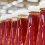 Many bottles of ketchup standing in a row in a factory